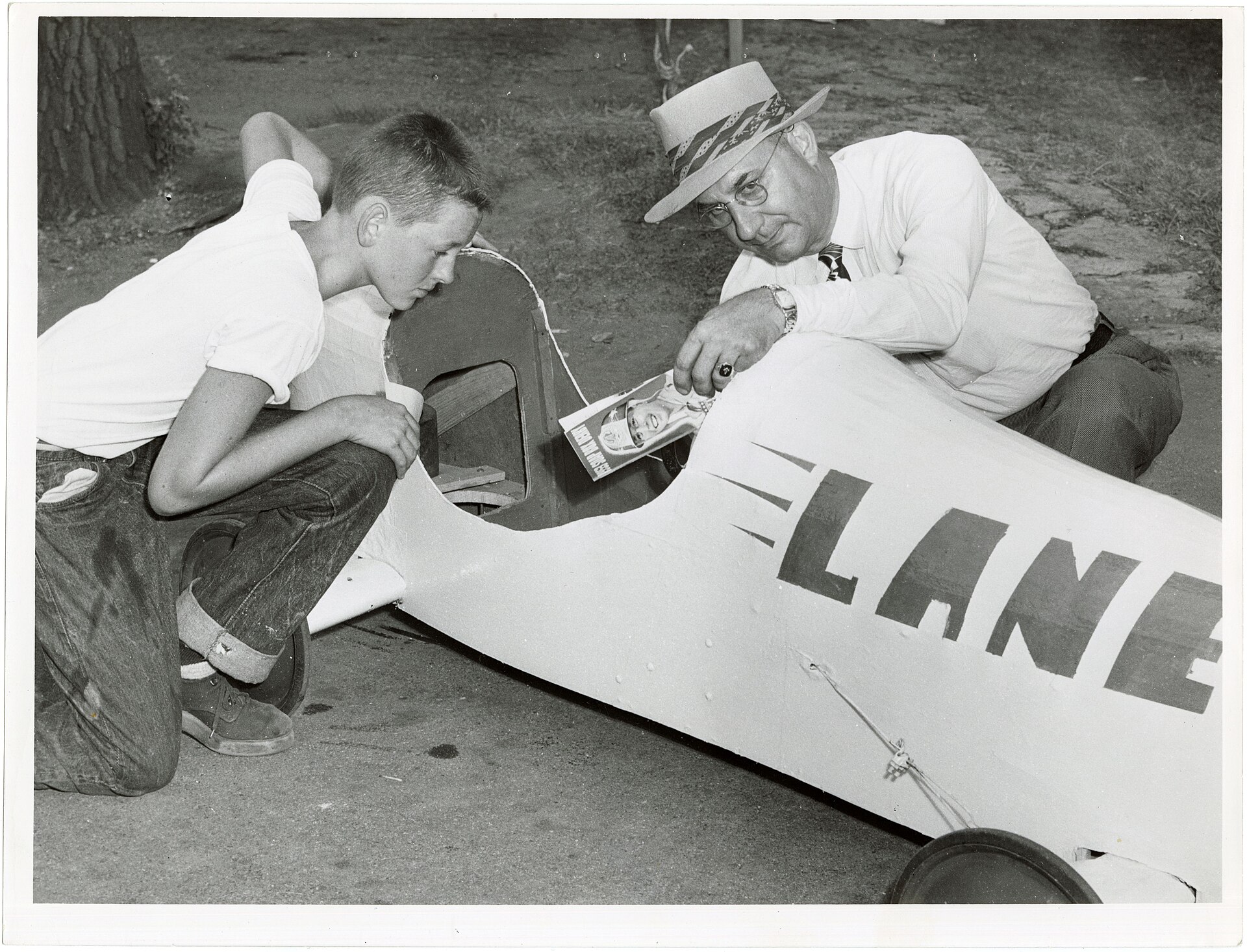 Fourteen-year-old Bruce Lane watches an official inspect the brake inside his streamlined Soap Box Derby car in 1953