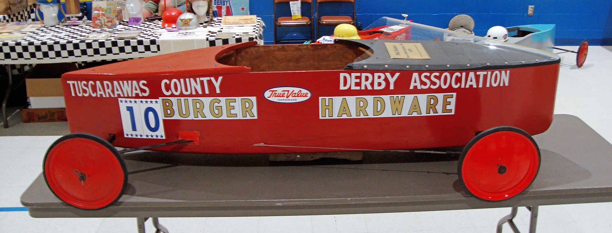 Long profile view of a 1976 Soap Box Derby world championship car fitted with a clear windscreen ahead of the driver opening